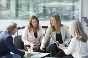 drei Frauen und ein Mann sitzen am Tisch und besprechen sich