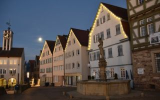 Marktplatz mit Fachwerkhäusern und Brunnen im Mondschein